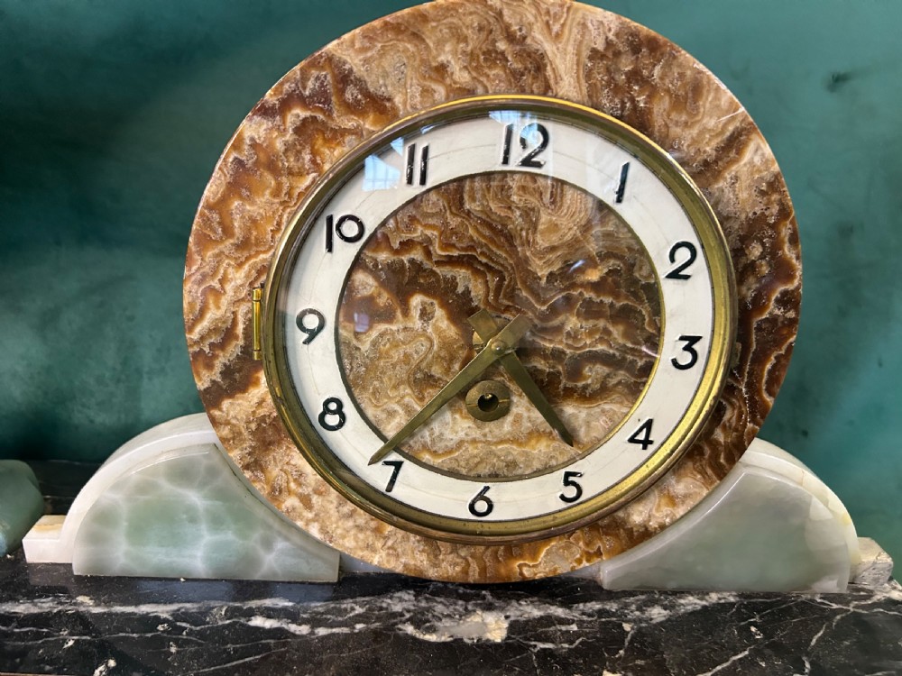 A French Art Deco three-piece clock garniture made of variegated brown marble and pale onyx, featuring a central spelter bird sculpture alongside a round clock face. View III