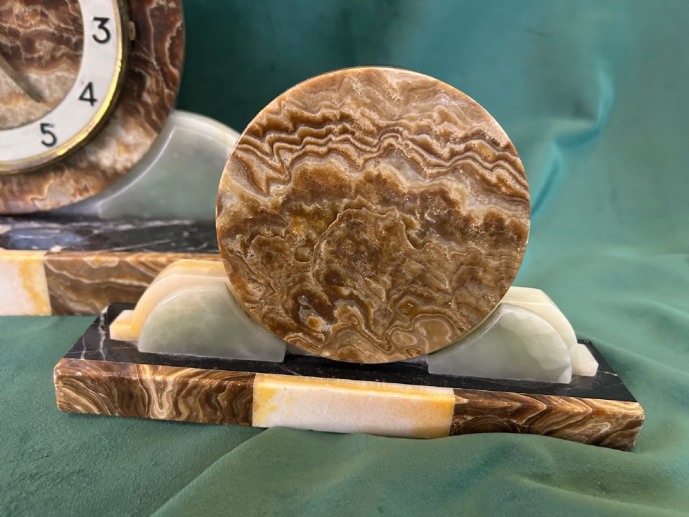 A French Art Deco three-piece clock garniture made of variegated brown marble and pale onyx, featuring a central spelter bird sculpture alongside a round clock face. View V
