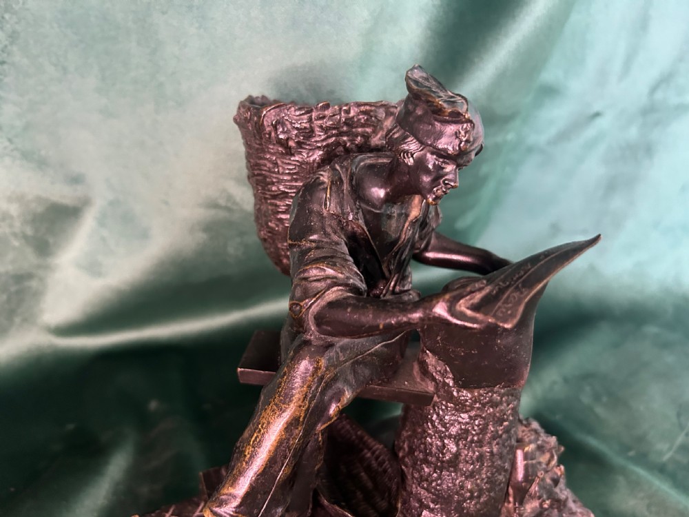 A patinated dark bronze sculpture depicting a seated man reading a newspaper, mounted on a black veined marble base. View IX