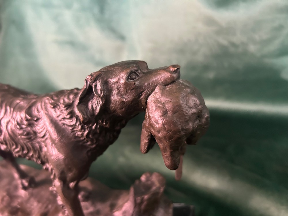 A cast bronze figure of a hunting dog holding a game bird in its jaws, set on a naturalistic ground base and mounted on a black veined marble plinth. View IV