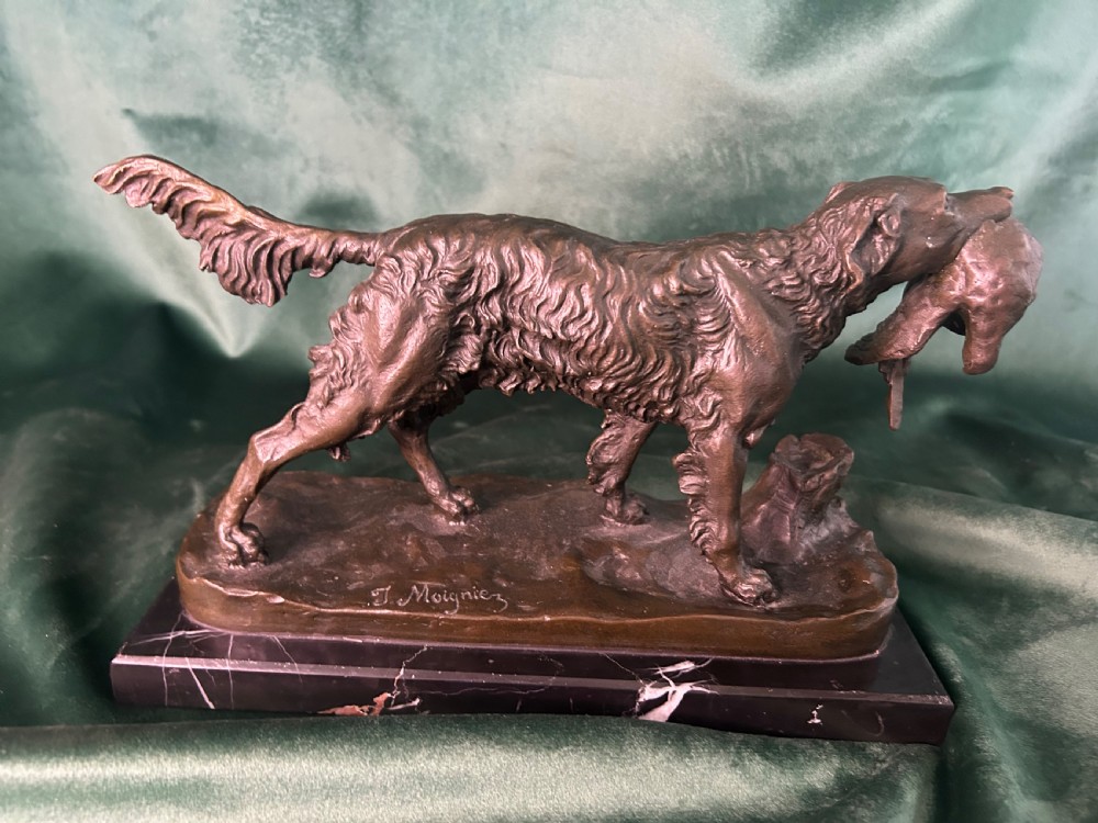 A cast bronze figure of a hunting dog holding a game bird in its jaws, set on a naturalistic ground base and mounted on a black veined marble plinth. View V