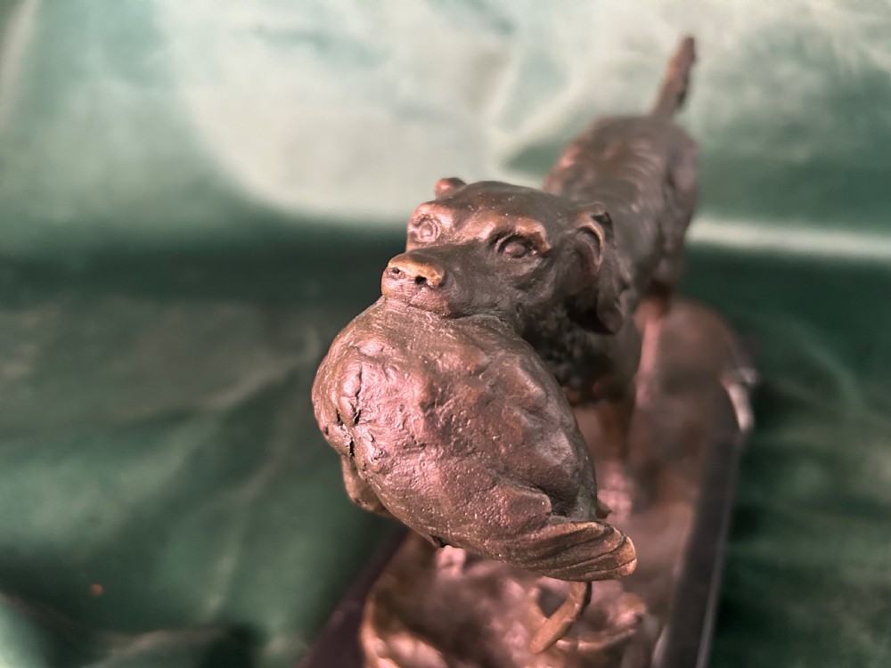 A cast bronze figure of a hunting dog holding a game bird in its jaws, set on a naturalistic ground base and mounted on a black veined marble plinth. View VI