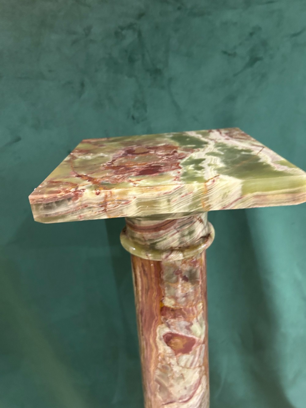 A tall variegated green onyx column pedestal featuring a square moulded top capital and a stepped square base. View III
