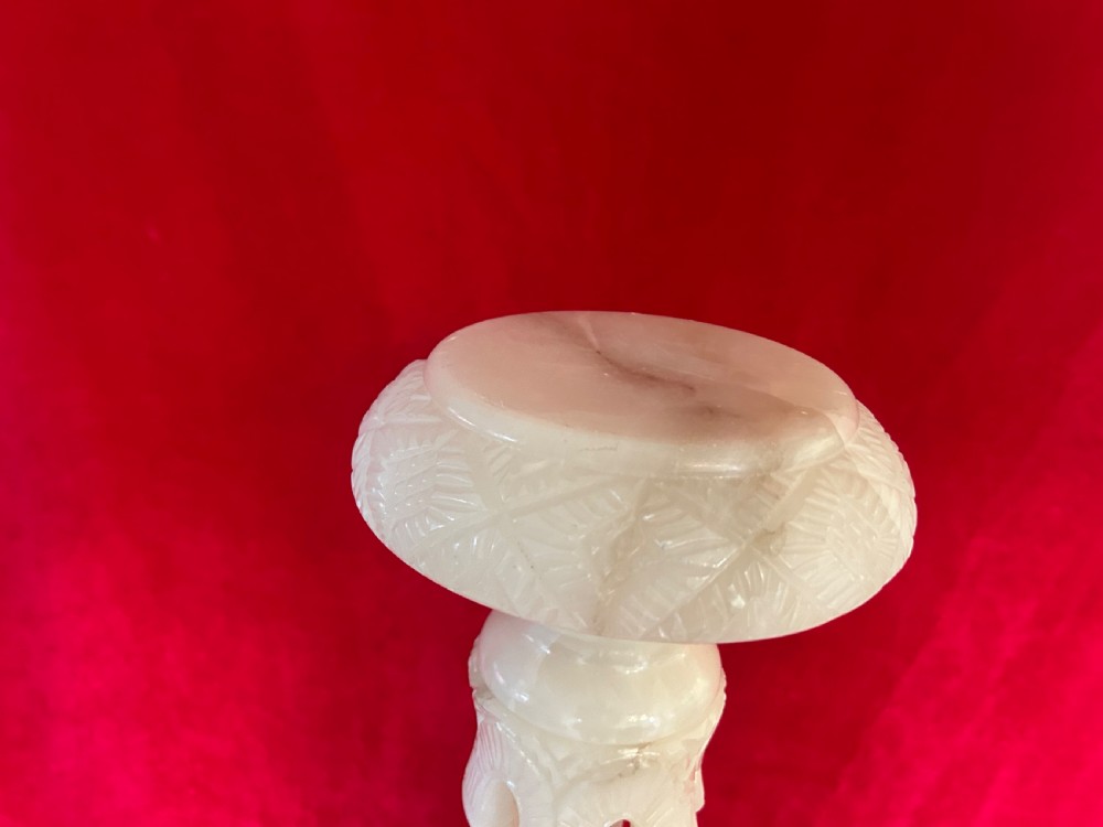 A tall carved cream alabaster plant stand featuring a round top, pierced central column, and stepped octagonal base. View V