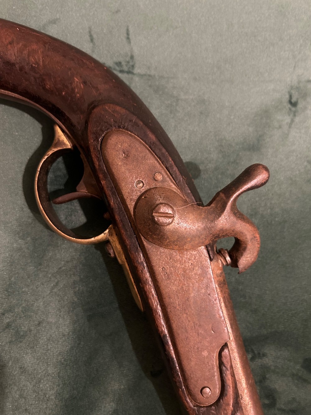 An antique single-barrel percussion pistol featuring a carved walnut stock, a metal hammer mechanism, and brass fittings along the trigger guard and butt cap. View II