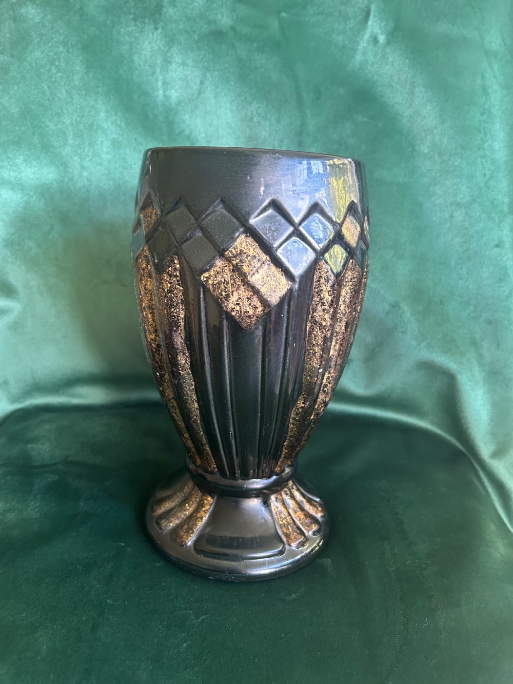 An Art Deco ceramic vase featuring a dark glaze with geometric diamond relief patterns highlighted in gold detailing.