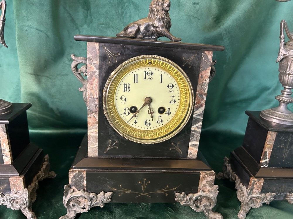 A three-piece French black slate clock garniture set comprising a central mantel clock topped with a lion figure and flanked by two matching multi-branch candelabra. View III