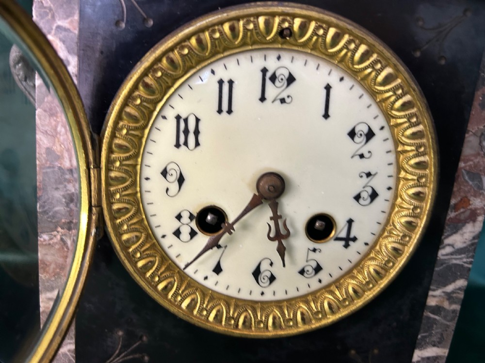 A three-piece French black slate clock garniture set comprising a central mantel clock topped with a lion figure and flanked by two matching multi-branch candelabra. View IV