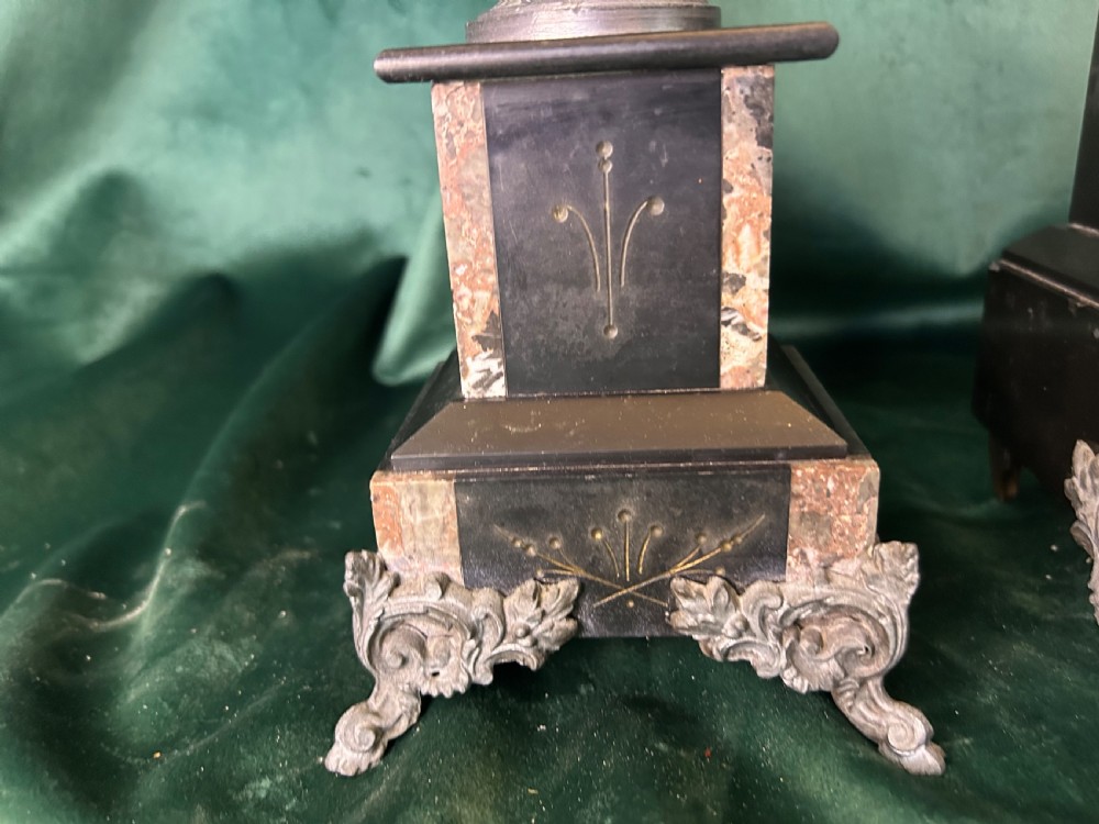A three-piece French black slate clock garniture set comprising a central mantel clock topped with a lion figure and flanked by two matching multi-branch candelabra. View V