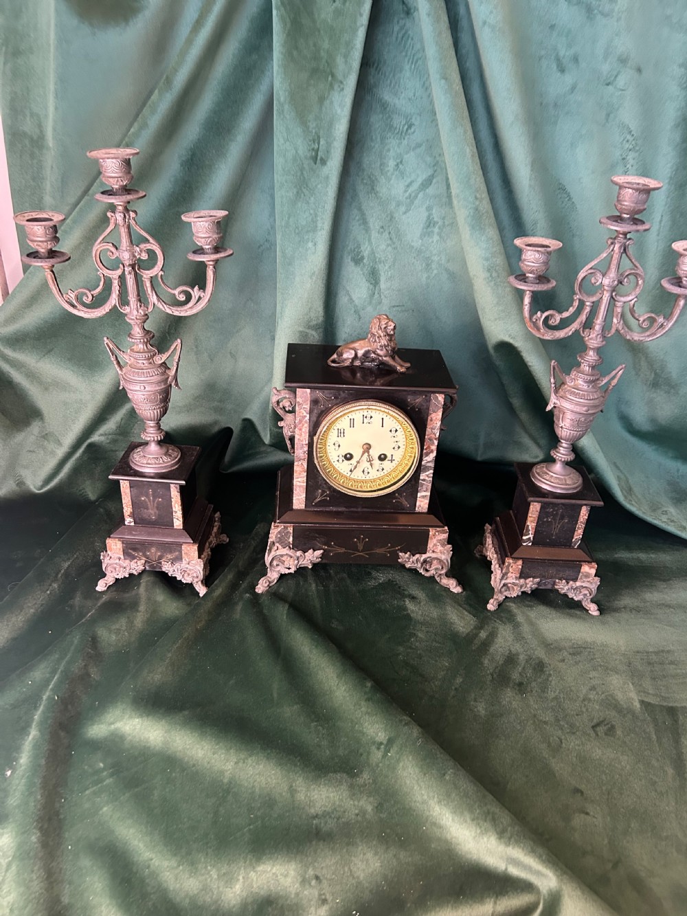 A three-piece French black slate clock garniture set comprising a central mantel clock topped with a lion figure and flanked by two matching multi-branch candelabra. View VI