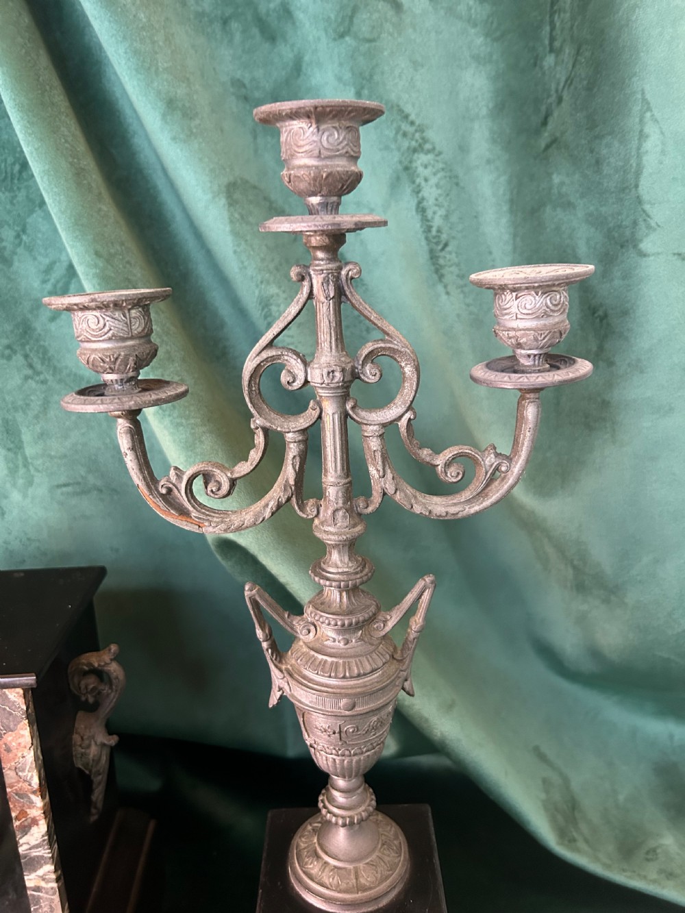 A three-piece French black slate clock garniture set comprising a central mantel clock topped with a lion figure and flanked by two matching multi-branch candelabra. View VII