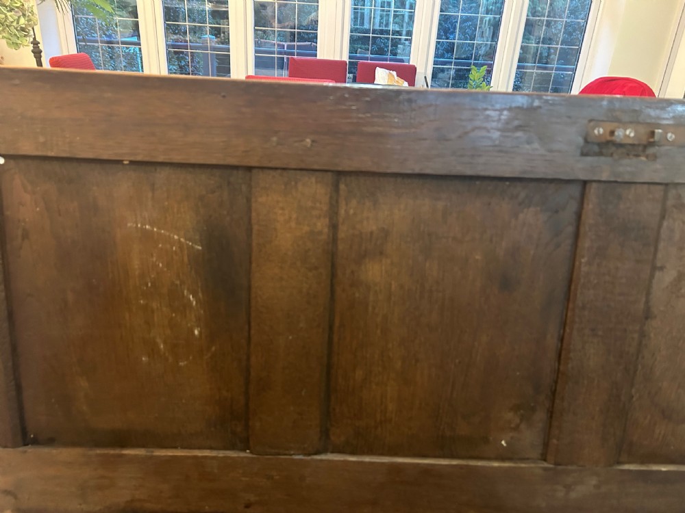 An 18th-century dark oak mule chest featuring a four-panel front, two base drawers with brass handles, and a hinged lid. View XIV
