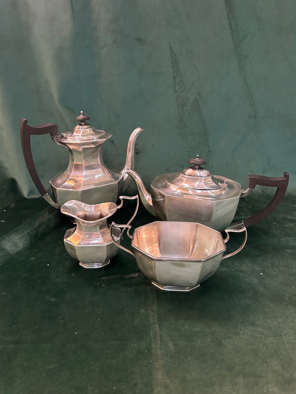 A four-piece Art Deco silver tea and coffee set featuring faceted octagonal bodies, dark wooden handles, and stepped lids.