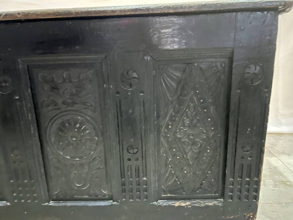 A dark carved wooden antique coffer featuring four rectangular front panels decorated with geometric lozenge and rosette motifs. View II