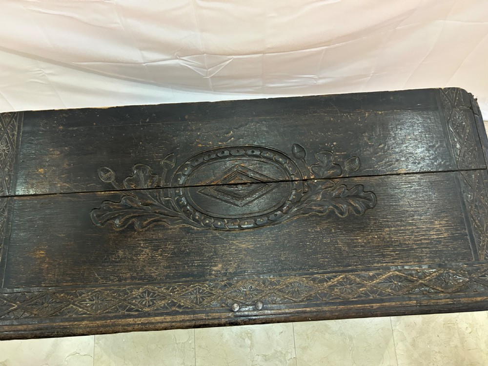 A dark carved wooden antique coffer featuring four rectangular front panels decorated with geometric lozenge and rosette motifs. View IV