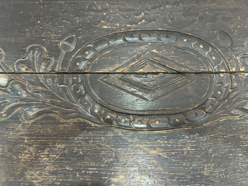 A dark carved wooden antique coffer featuring four rectangular front panels decorated with geometric lozenge and rosette motifs. View V