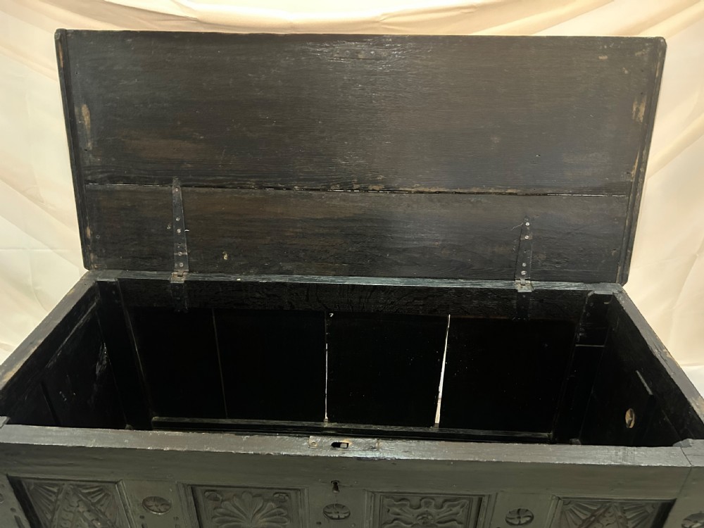 A dark carved wooden antique coffer featuring four rectangular front panels decorated with geometric lozenge and rosette motifs. View IX