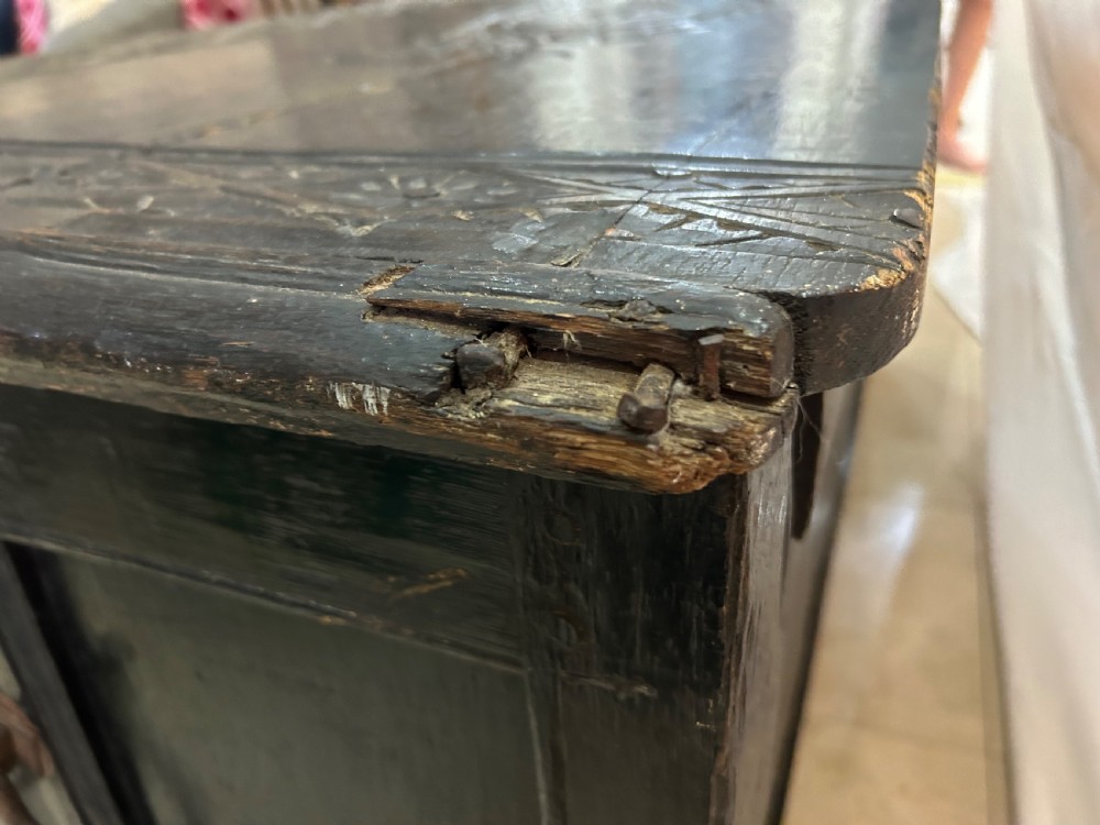 A dark carved wooden antique coffer featuring four rectangular front panels decorated with geometric lozenge and rosette motifs. View X
