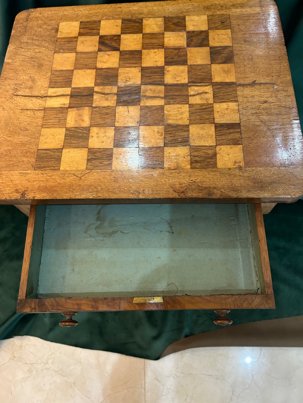 A Victorian warm brown wood games work table featuring an inlaid chessboard top, a single drawer, a damask fabric sewing well, and a turned pedestal base. View III