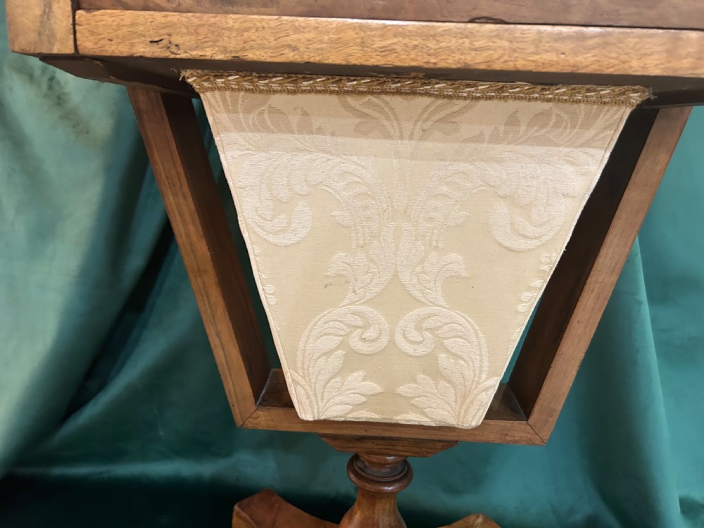A Victorian warm brown wood games work table featuring an inlaid chessboard top, a single drawer, a damask fabric sewing well, and a turned pedestal base. View V