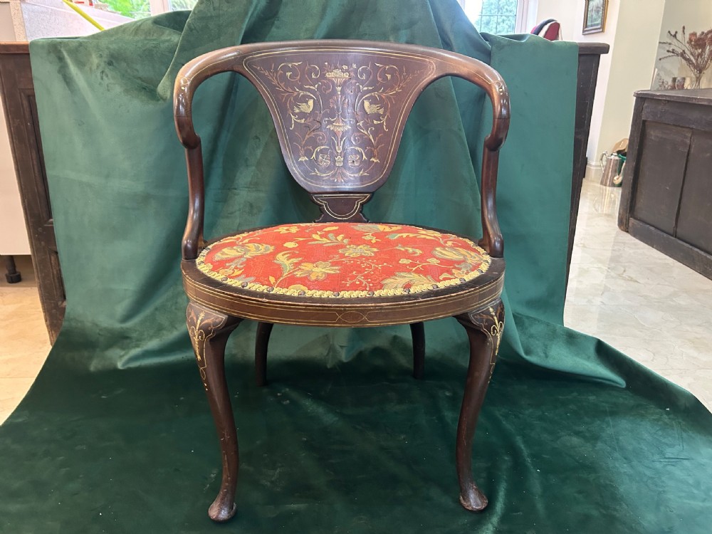 A nineteenth-century dark mahogany tub chair featuring intricate floral marquetry on the back splat and cabriole legs, fitted with a red floral upholstered seat.