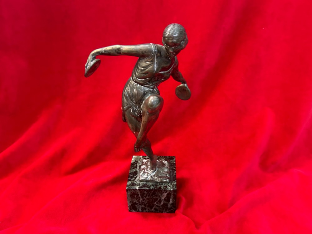 An Art Deco silver-plated figure of a female dancer balanced on one foot atop a square dark marble base.
