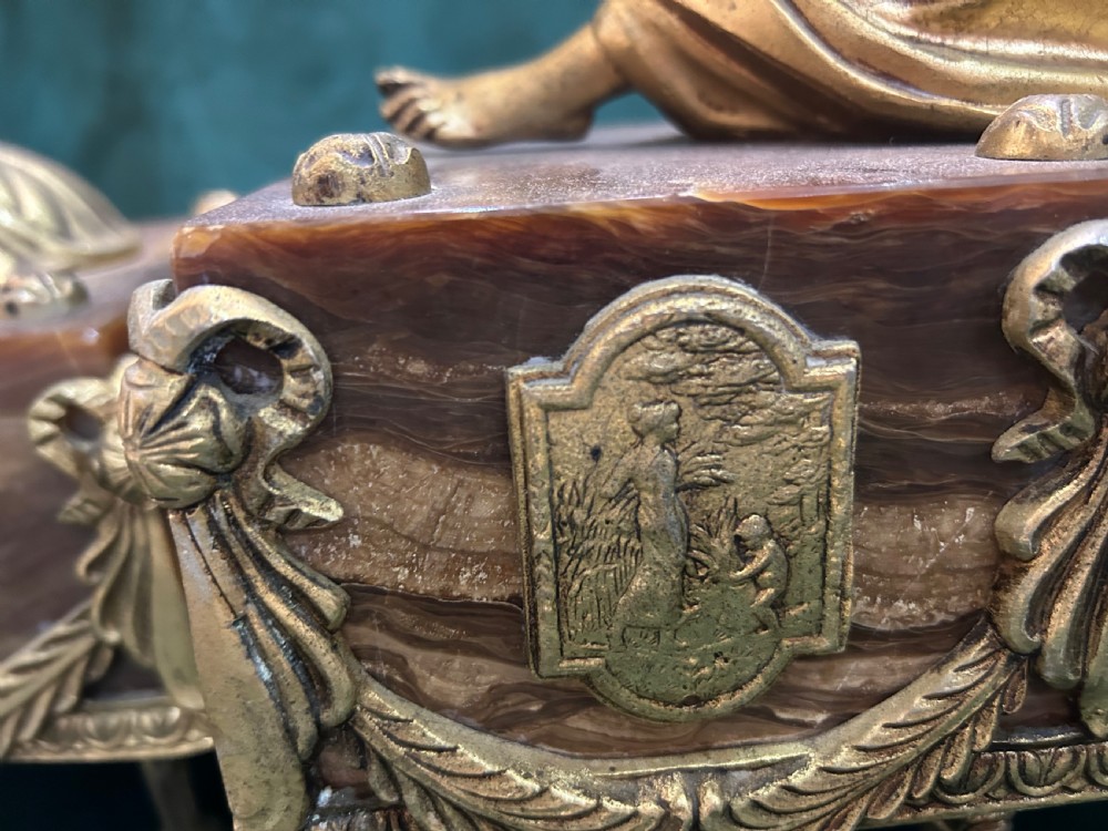 An antique three-piece French ormolu clock garniture featuring a central mantel clock decorated with a classical female figurine and marble base, flanked by two matching five-arm candelabra. View VII