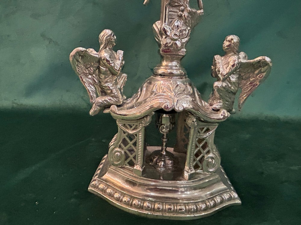 An antique silver metal standing altar cross featuring shell motif terminals, a figure of Christ, and two kneeling angels on a moulded pedestal base. View II