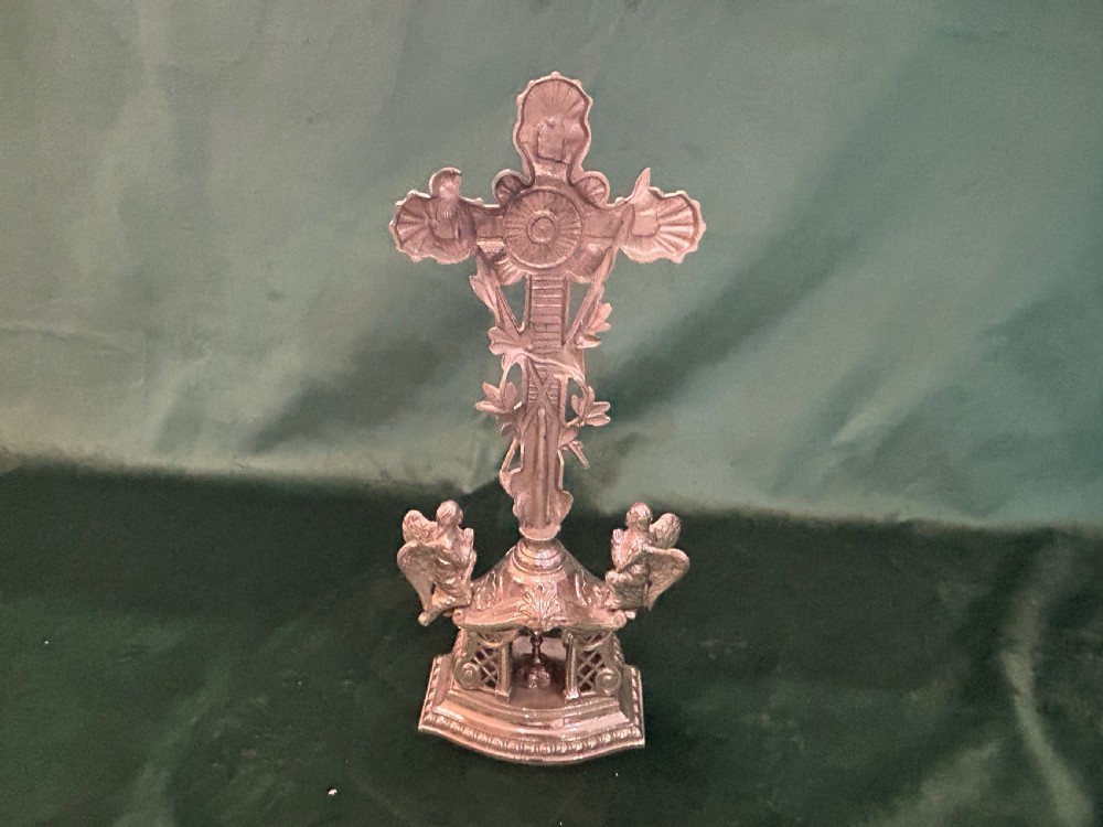 An antique silver metal standing altar cross featuring shell motif terminals, a figure of Christ, and two kneeling angels on a moulded pedestal base. View V