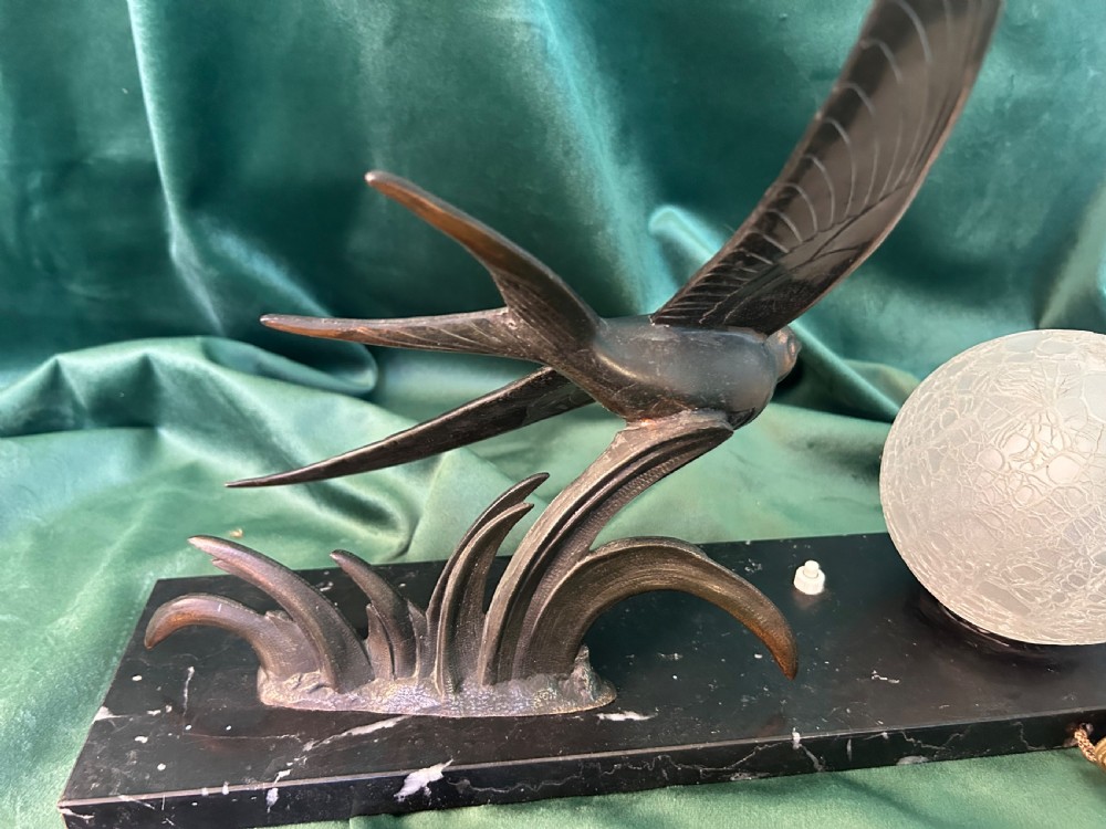An Art Deco table lamp featuring a patinated metal bird in flight beside a spherical frosted glass globe on a black marble base. View III