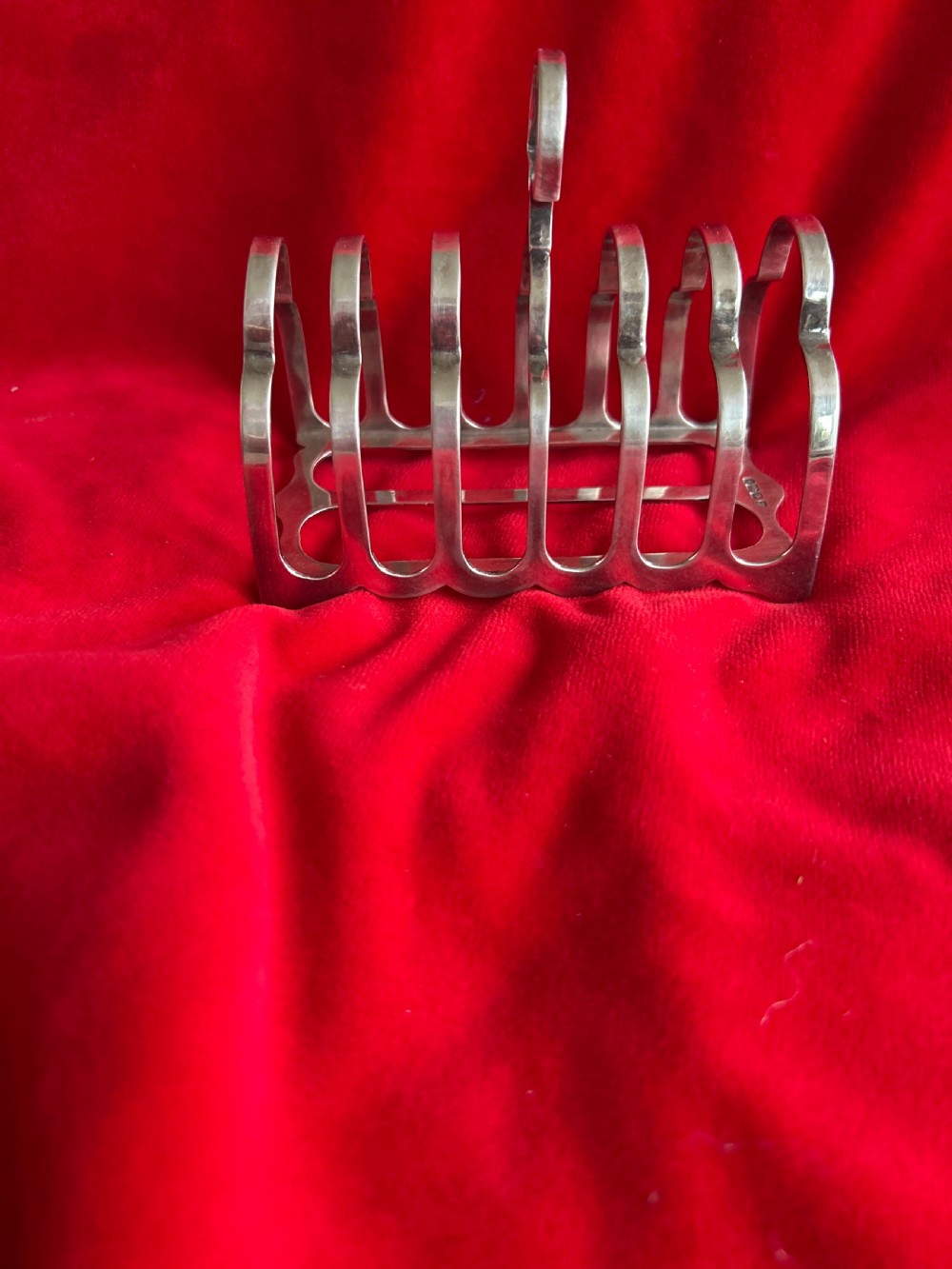 A polished silver toast rack featuring arched wire dividers, a central ring handle, and a six-slice capacity.