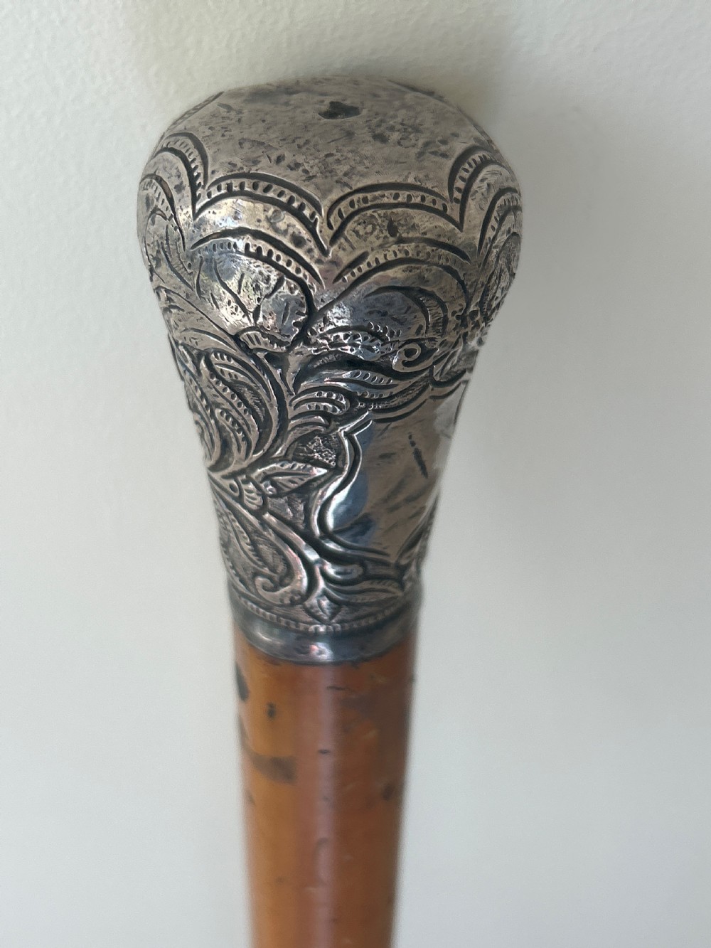A Victorian walking cane featuring a tapered malacca wood shaft topped with an embossed silver pommel handle. View III