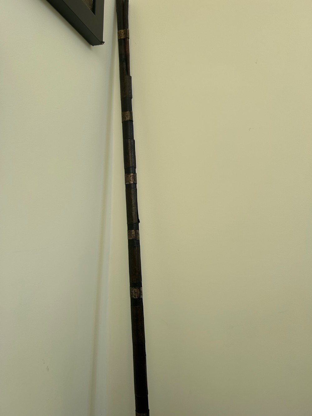 An antique Afghan flintlock Jezail rifle featuring a curved wooden stock adorned with embossed metalwork, a long iron barrel, and a traditional firing mechanism. View II