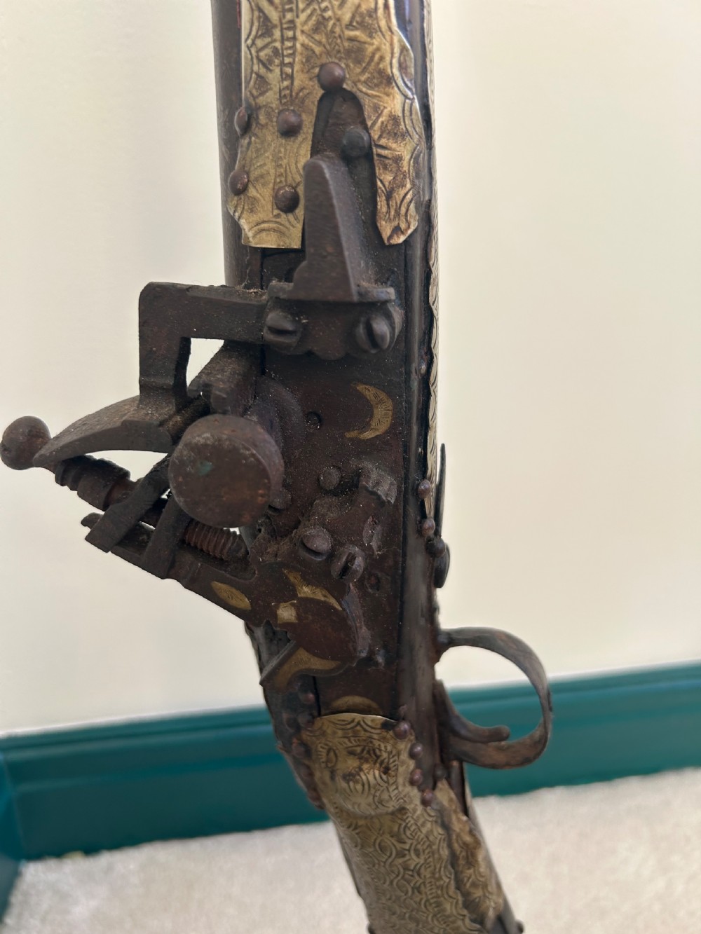 An antique Afghan flintlock Jezail rifle featuring a curved wooden stock adorned with embossed metalwork, a long iron barrel, and a traditional firing mechanism. View IV