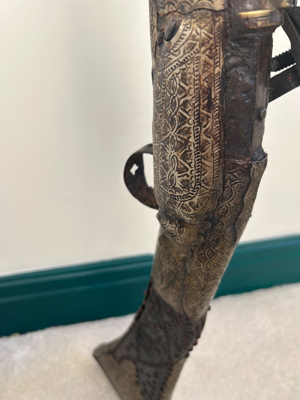 An antique Afghan flintlock Jezail rifle featuring a curved wooden stock adorned with embossed metalwork, a long iron barrel, and a traditional firing mechanism. View VI