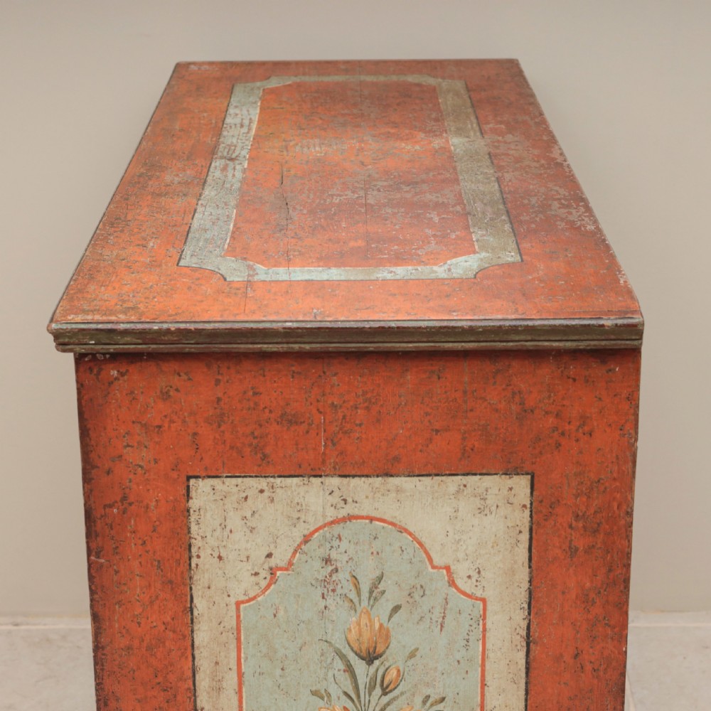 A 19th-century terracotta red painted wooden cabinet featuring two upper drawers and two cupboard doors adorned with cream panels hand-painted with floral urn designs. View III