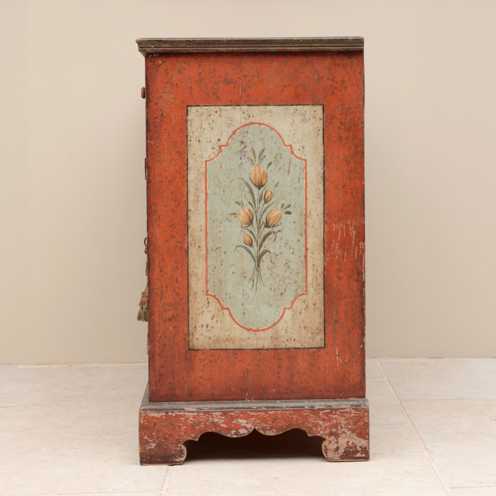 A 19th-century terracotta red painted wooden cabinet featuring two upper drawers and two cupboard doors adorned with cream panels hand-painted with floral urn designs. View V