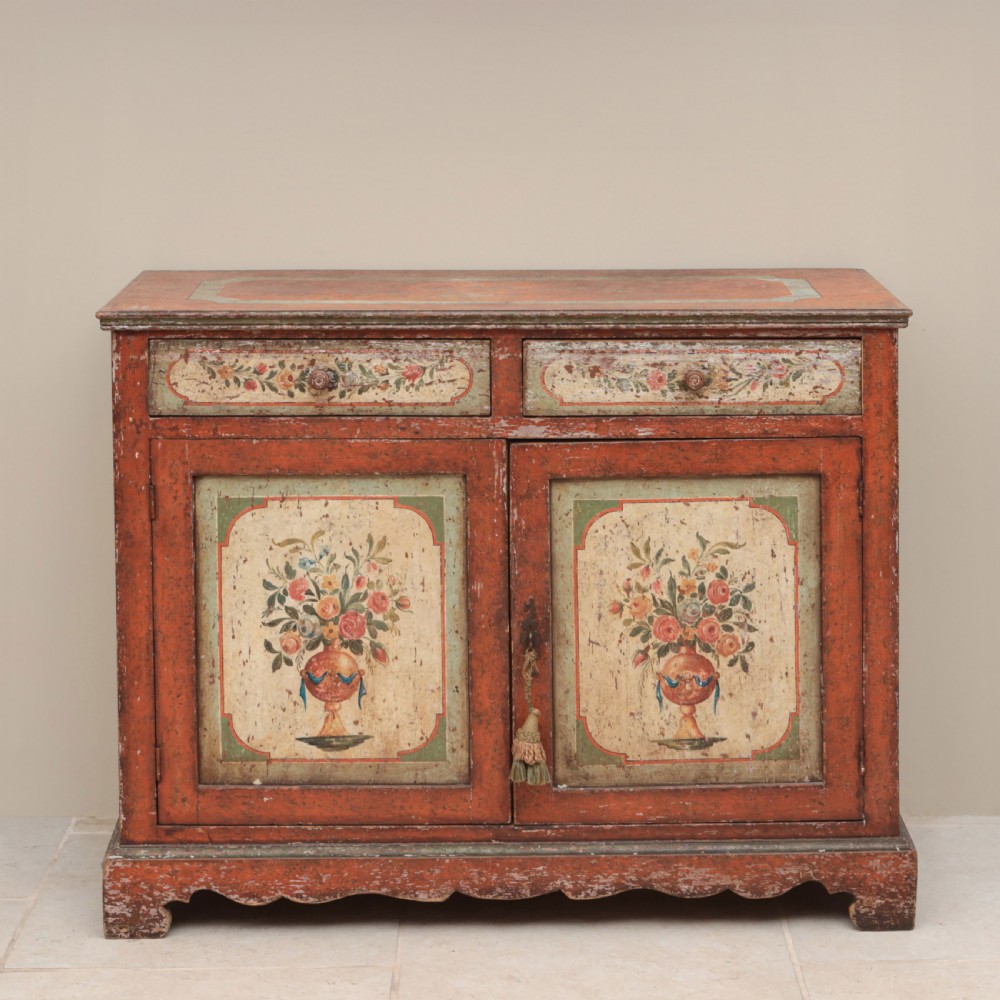 A 19th-century terracotta red painted wooden cabinet featuring two upper drawers and two cupboard doors adorned with cream panels hand-painted with floral urn designs. View VII