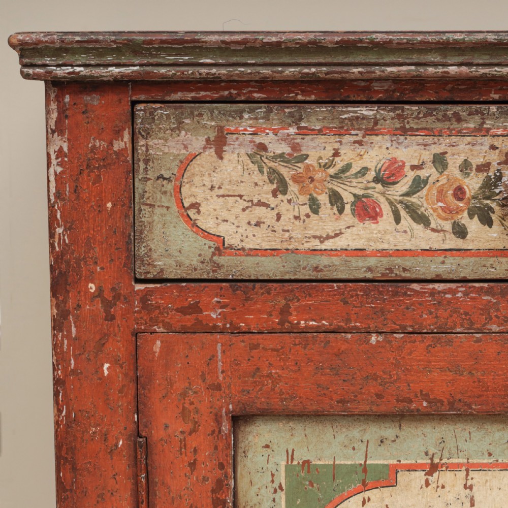 A 19th-century terracotta red painted wooden cabinet featuring two upper drawers and two cupboard doors adorned with cream panels hand-painted with floral urn designs. View VIII