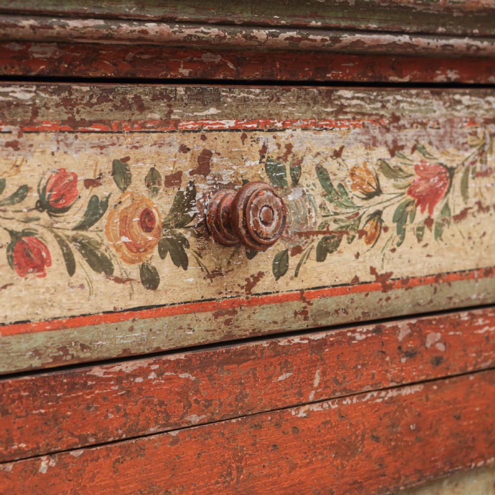 A 19th-century terracotta red painted wooden cabinet featuring two upper drawers and two cupboard doors adorned with cream panels hand-painted with floral urn designs. View XII