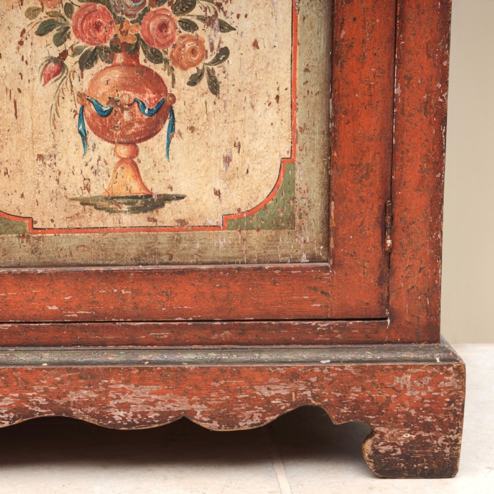 A 19th-century terracotta red painted wooden cabinet featuring two upper drawers and two cupboard doors adorned with cream panels hand-painted with floral urn designs. View XIII