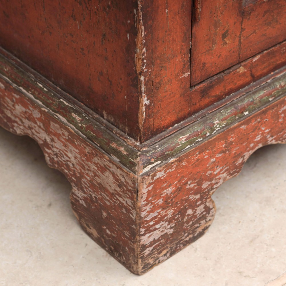 A 19th-century terracotta red painted wooden cabinet featuring two upper drawers and two cupboard doors adorned with cream panels hand-painted with floral urn designs. View XVI