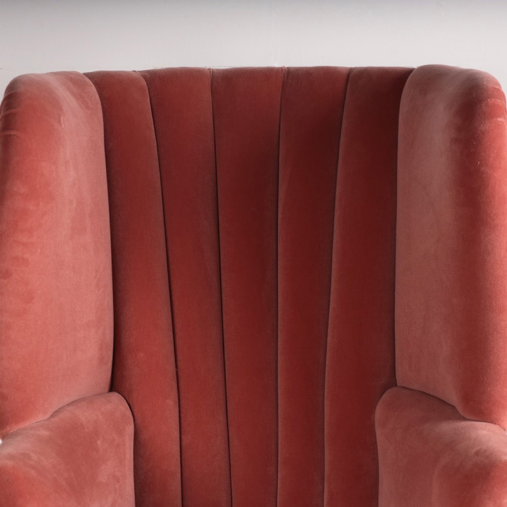 An 18th-century style barrel back armchair upholstered in dusty pink velvet with vertical channel quilting, standing on wooden legs with brass castors. View V