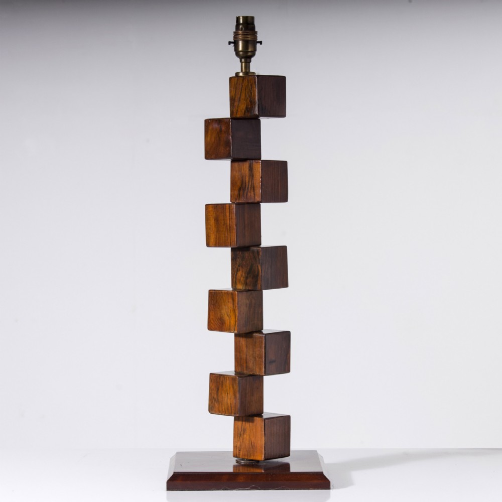 A mid-century modern wooden table lamp base constructed from offset stacked cubes terminating in a brass bulb fitting on a rectangular plinth.