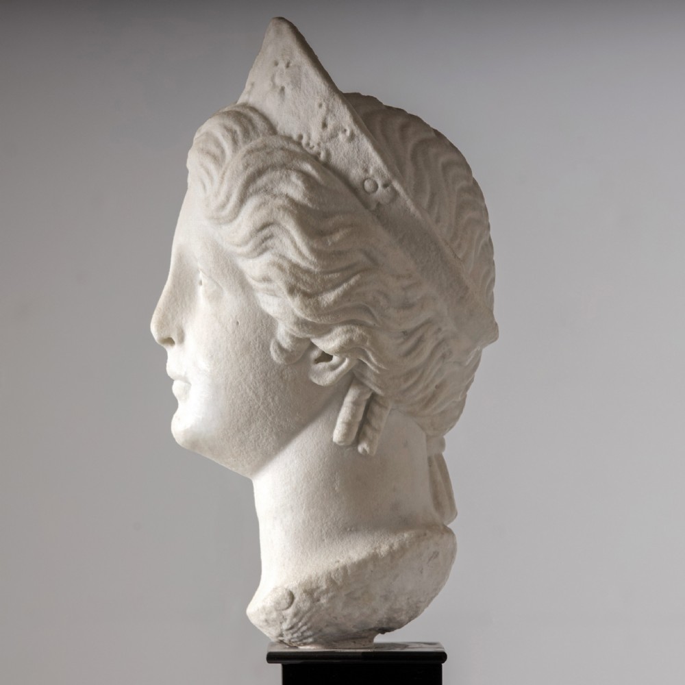 An off-white carved marble bust depicting the goddess Juno with wavy hair and a diadem, mounted on a square black marble plinth. View III