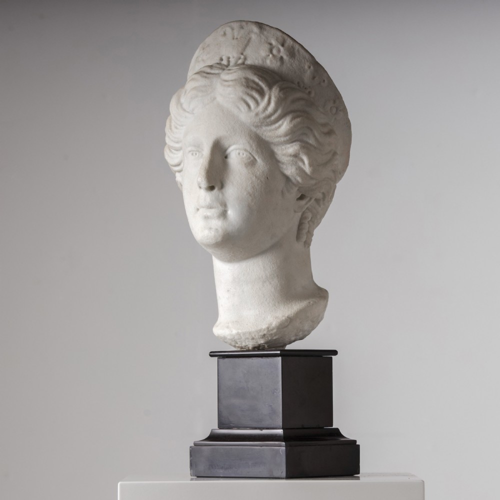 An off-white carved marble bust depicting the goddess Juno with wavy hair and a diadem, mounted on a square black marble plinth. View V