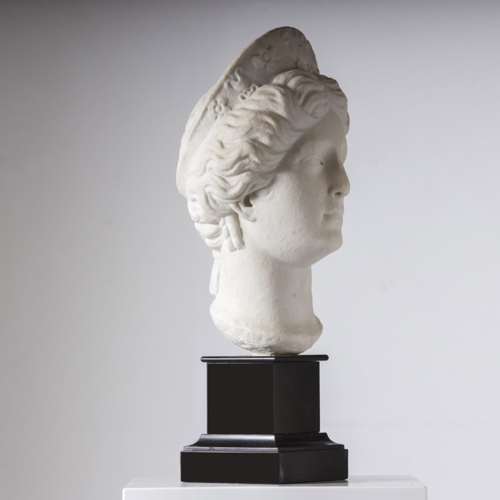 An off-white carved marble bust depicting the goddess Juno with wavy hair and a diadem, mounted on a square black marble plinth. View VII