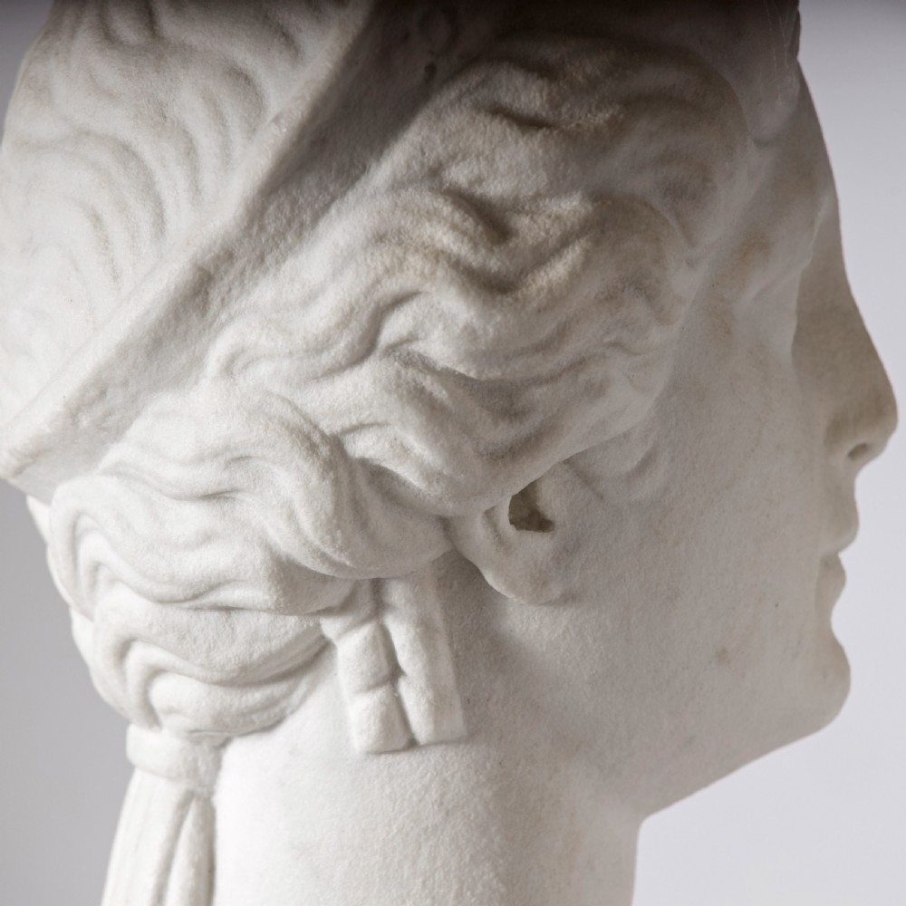 An off-white carved marble bust depicting the goddess Juno with wavy hair and a diadem, mounted on a square black marble plinth. View VIII