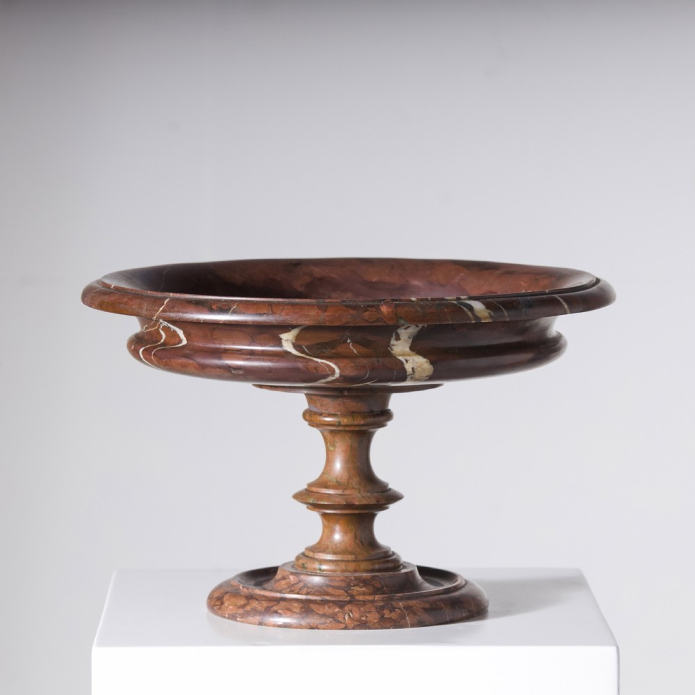 A carved reddish-brown marble tazza featuring a wide shallow dish, turned central stem, and circular moulded base.