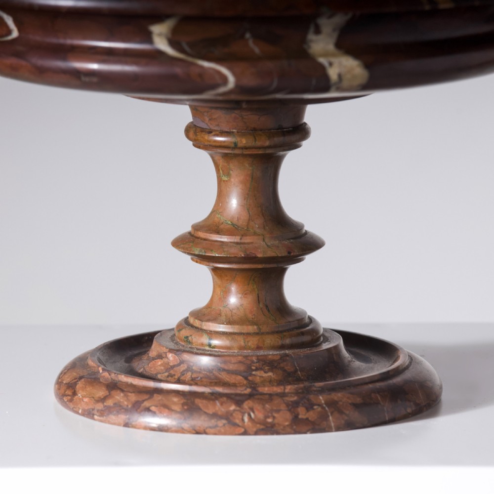 A carved reddish-brown marble tazza featuring a wide shallow dish, turned central stem, and circular moulded base. View V